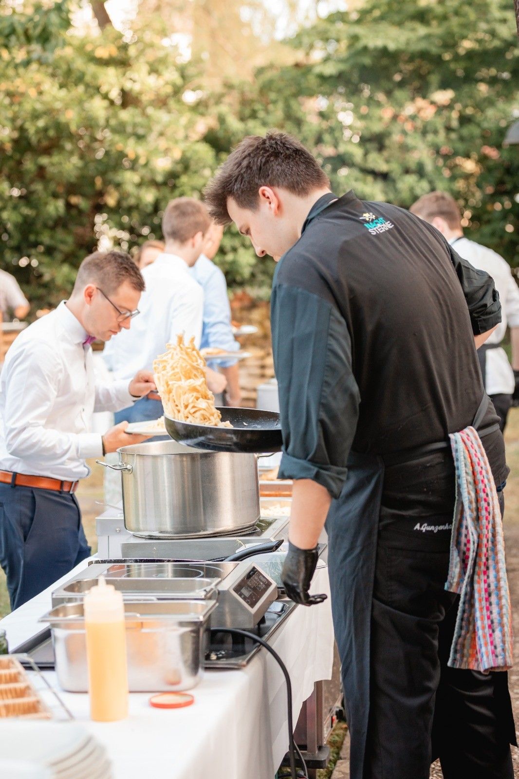 Koch schwenkt Pasta in der Pfanne beim Live-Cooking